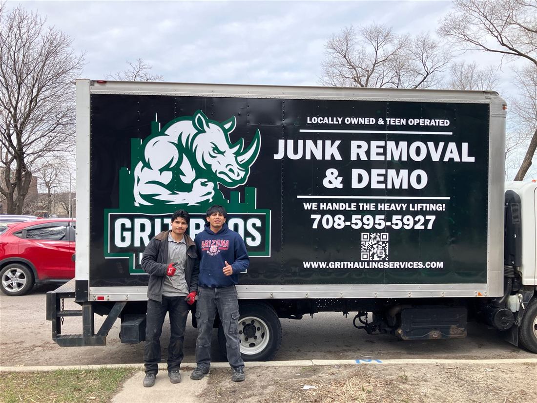 The Grit Bros Hauling founders standing in front of their branded junk removal box truck in Chicago